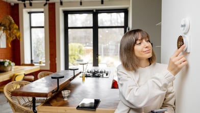 Frau reguliert die Temperatur in ihrer Wohnung mithilfe eines elektronischen Thermostats