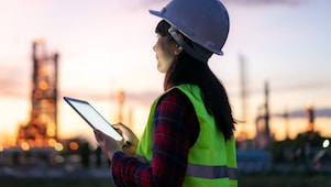 Eine Frau sitzt in einem hellen Raum vor einem Computer.