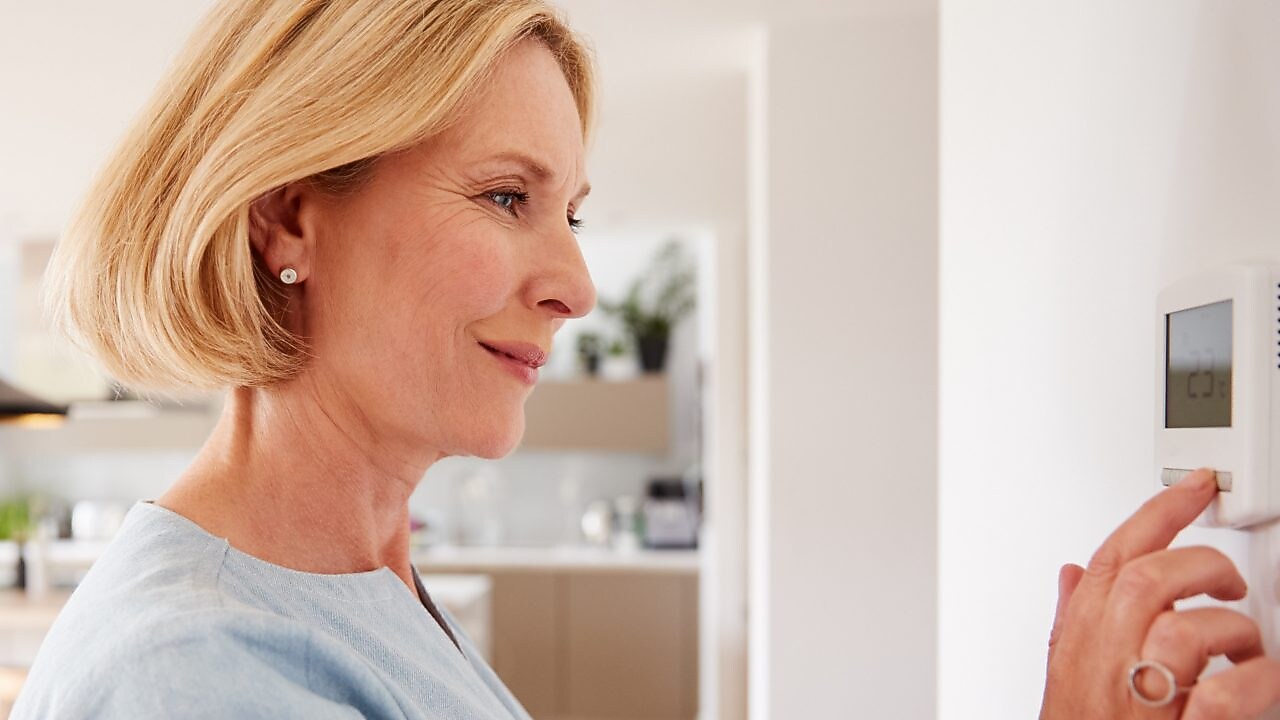 Eine Frau stellt ihr Thermostat ein.