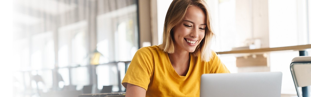 Junge Frau blickt lächelnd in Ihr Notebook