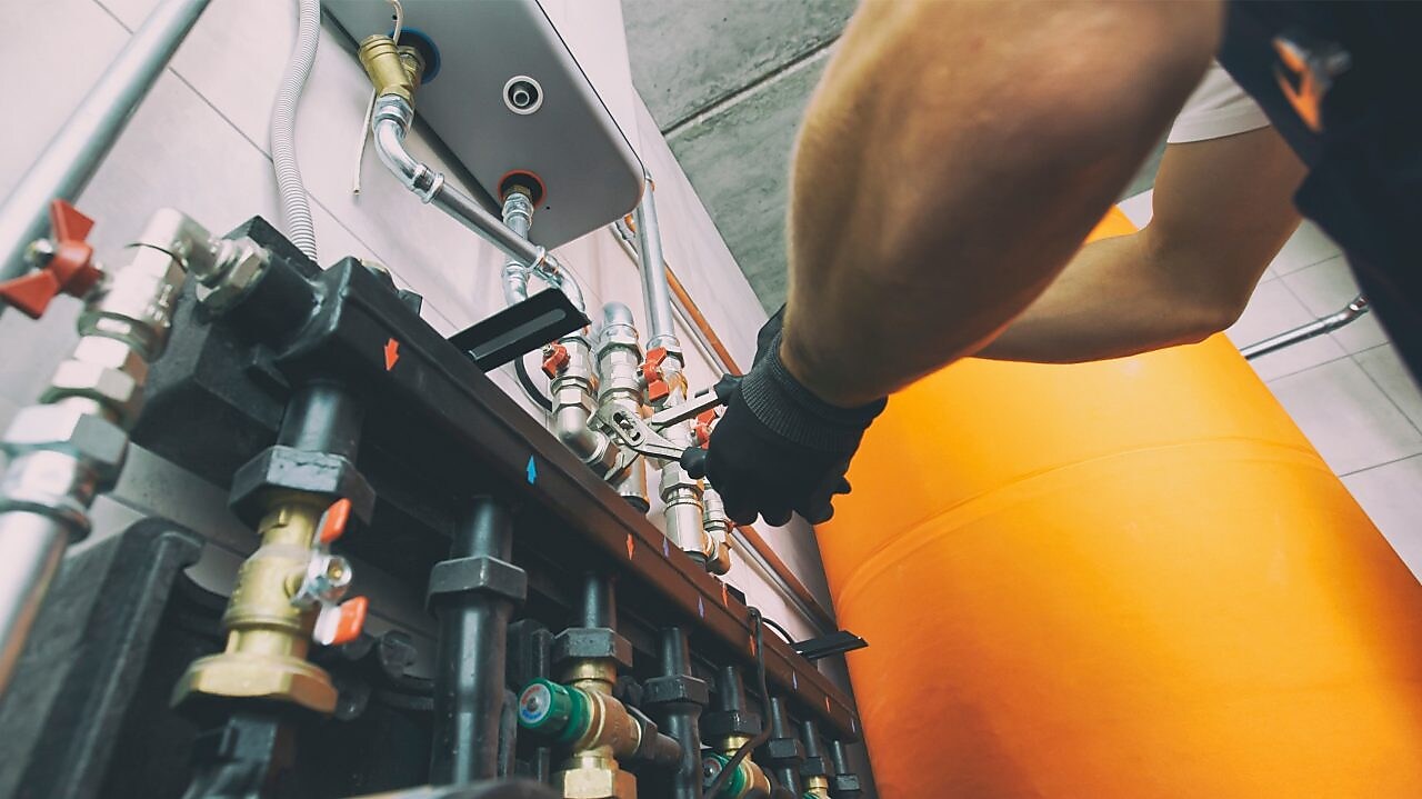 Ein Mann im Blaumann  arbeitet an einer Ölheizung