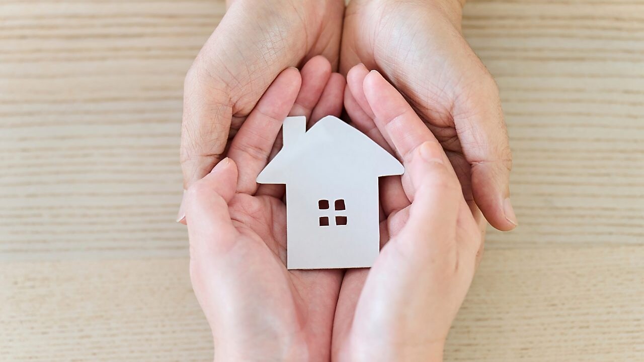 Ein Modellhaus wird in den insgesamt vier Händen gehalten