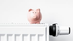 Sparschwein steht auf Heizkörper mit Thermostat