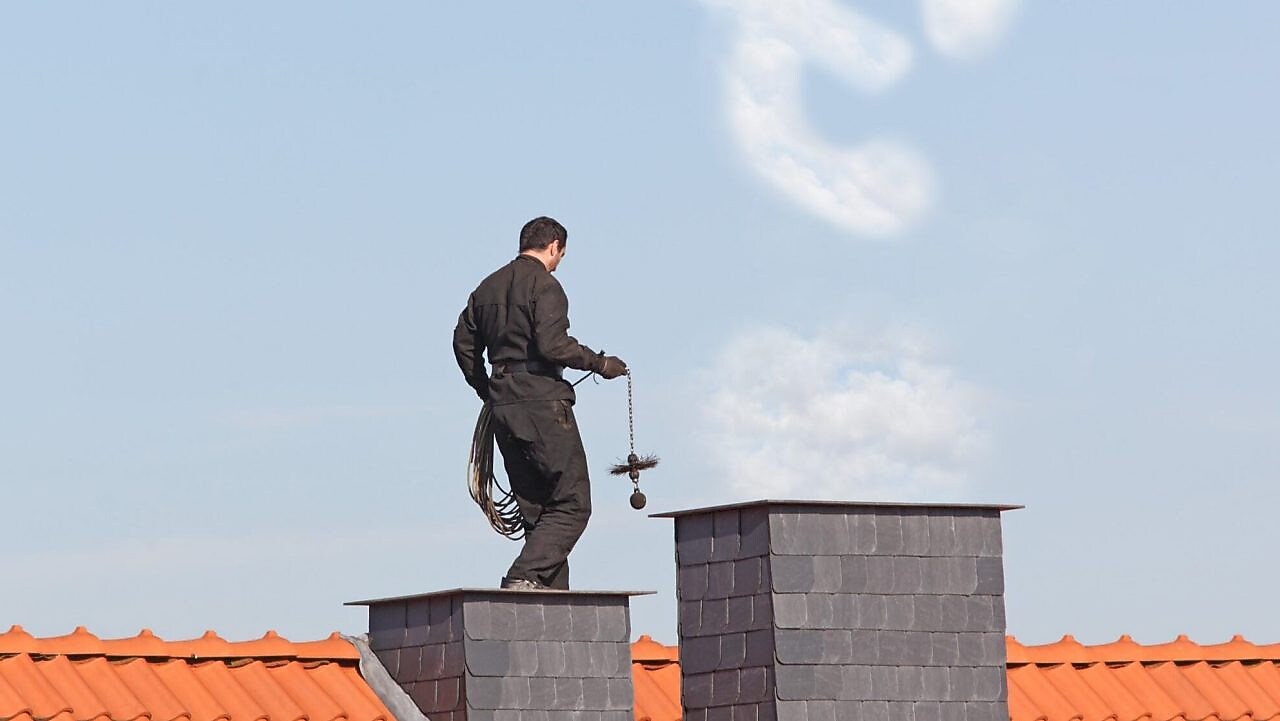 Schornsteinfeger auf dem Dach eines Hauses 