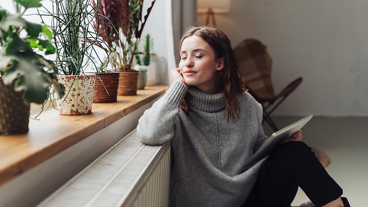Eine Frau lehnt sich an ihre Heizung
