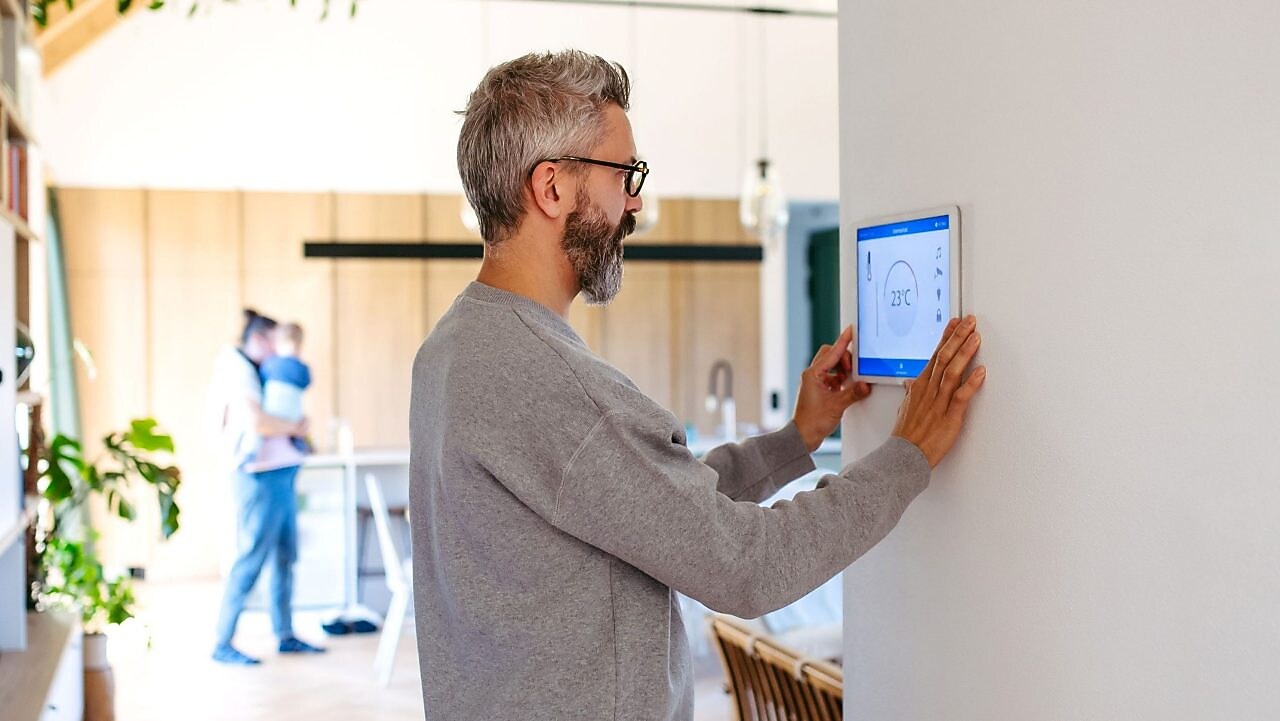 Mann benutzt Smart-Home-Bedienfeld