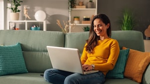 Frau sitzt mit Laptop auf einem mintgrünen Sofa 