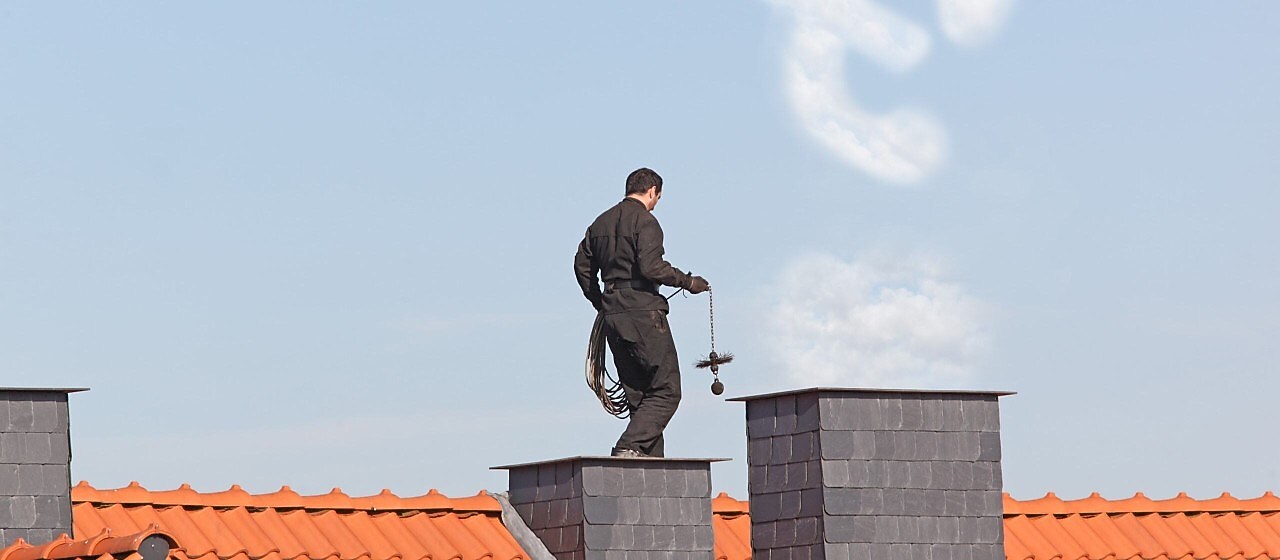 Schornsteinfeger auf dem Dach eines Hauses