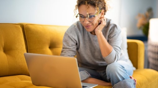 Frau sitzt mit Laptop auf einem Sofa 
