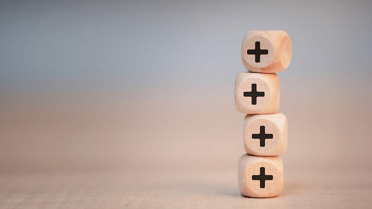 Vier aufeinandergestapelte Würfel mit einem Pluszeichen