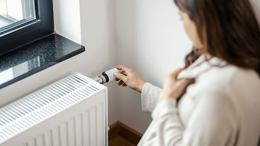 Frau erhöht Temperatur am Heizkörper in ihrer Wohnung