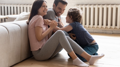 Vater, Mutter und Sohn spielen auf dem Fußboden eines Wohnzimmers