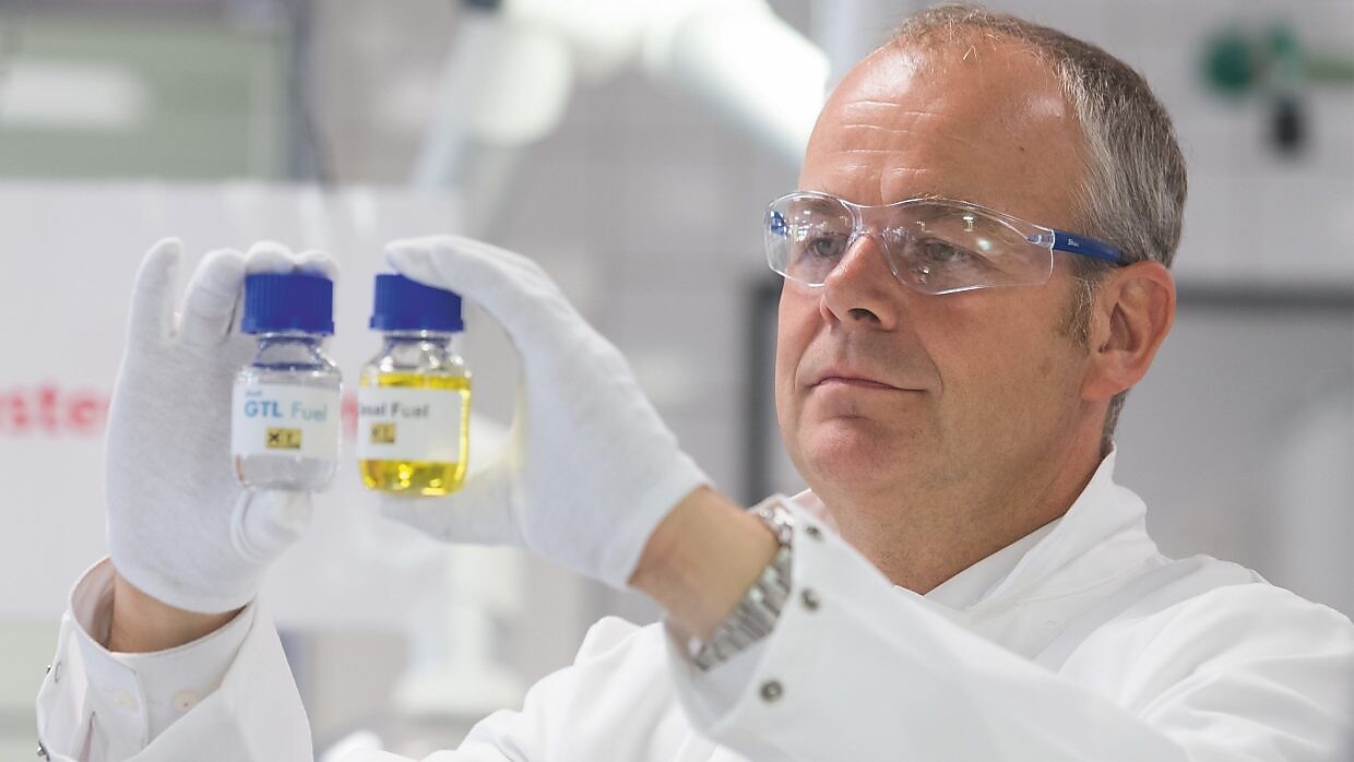 Ein Labormitarbeiter hält zwei Probefläschchen hoch und vergleicht deren Inhalt.