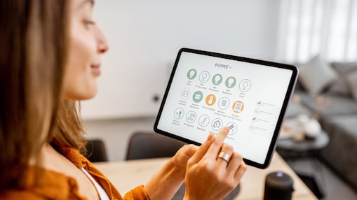 Junge Frau steuert Geräte ihres Zuhauses über ein Tablet.