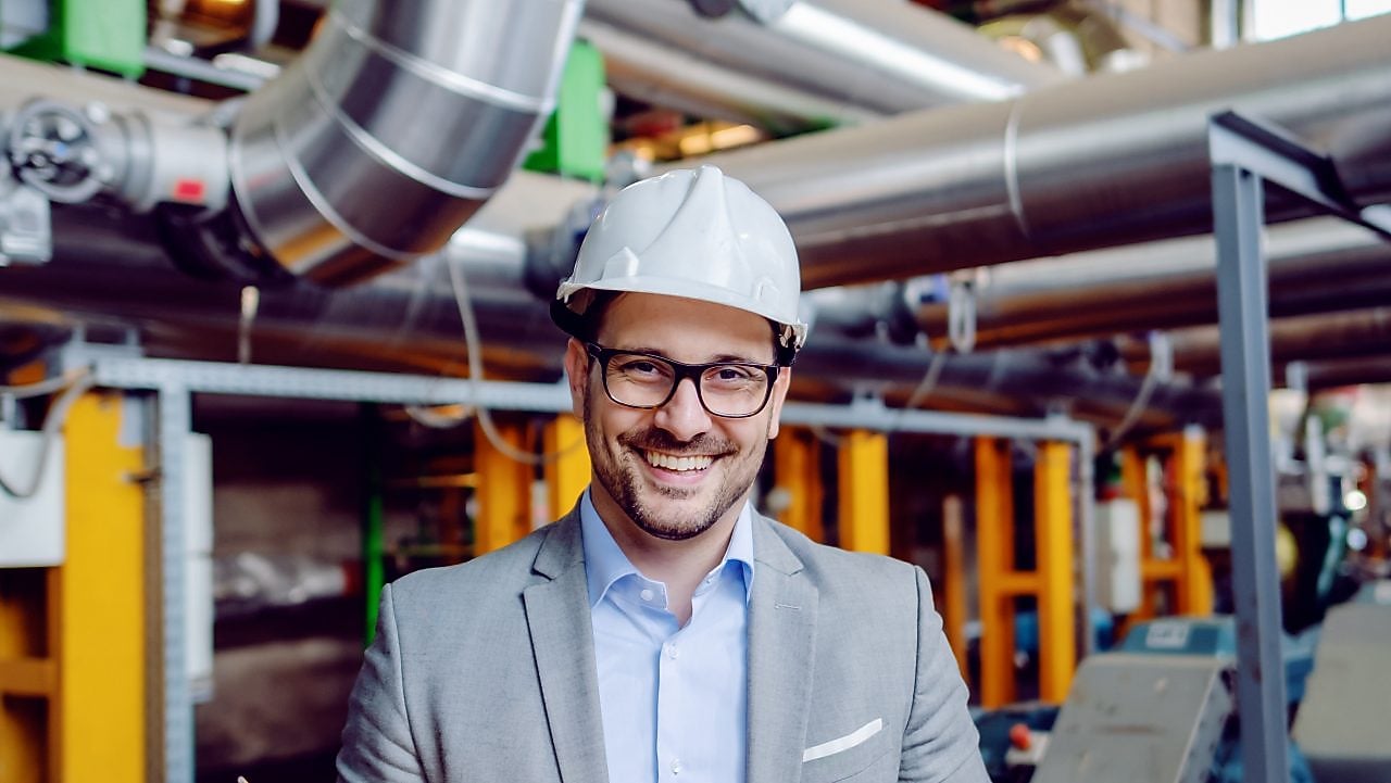 Mann mit Helm auf dem Kopf und Brille lächelt in die Kamera