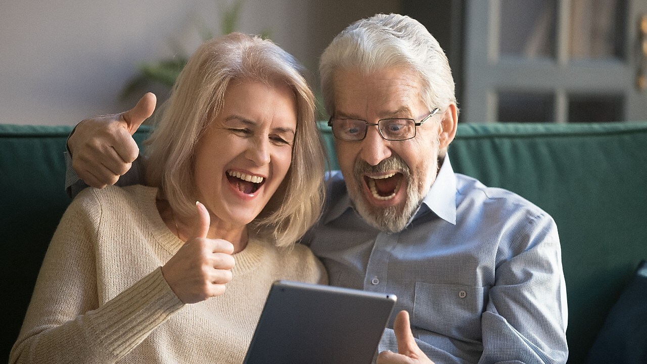 Ehepaar freut sich über Tablet gebeut dasitzend