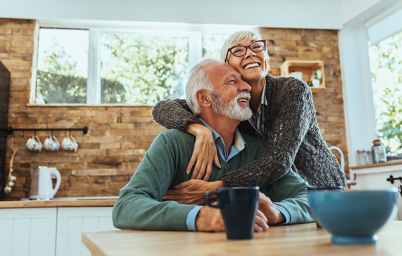 Ein Senioren Paar umarmt sich glücklich in der Küche