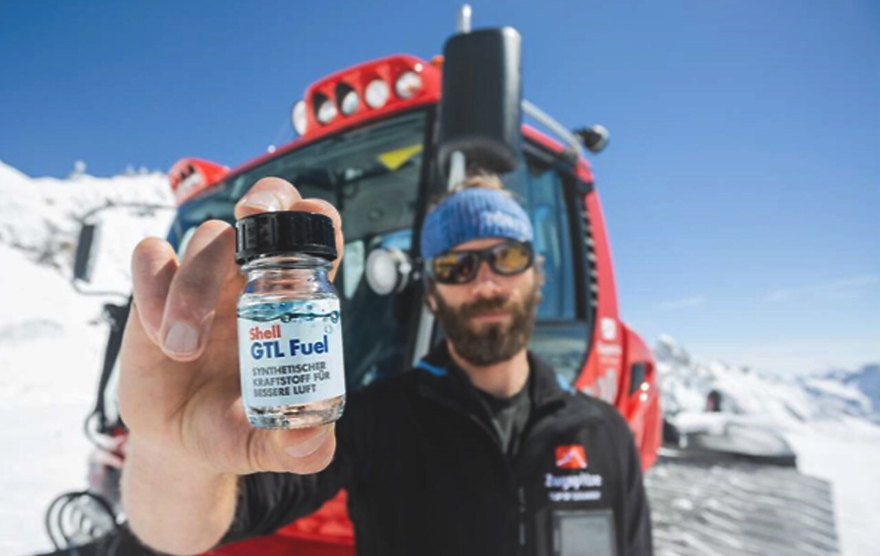 Mann im Schee hält kleine Glasfasche mit Shell GTL Heating Fuel in die Kamera