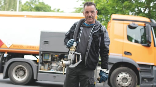 Heizöl Tankwagenfahrer läuft mit dem Schlauch zum Heizungskeller