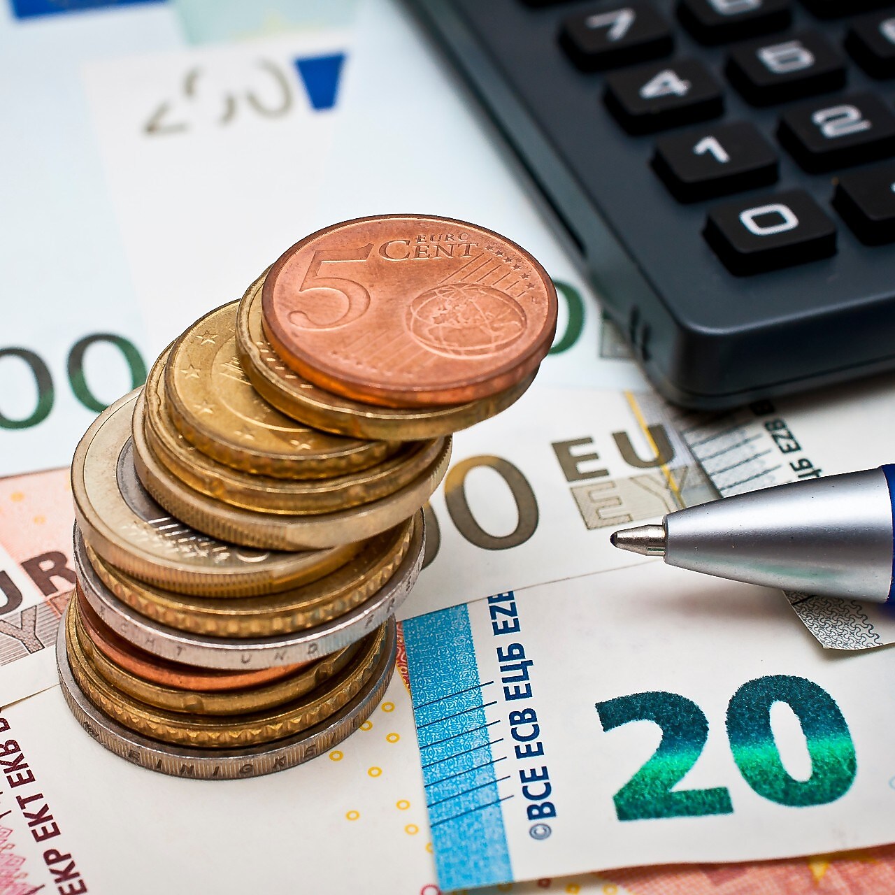 Geldmünzen und –scheine mit Taschenrechner und Kugelschreiber
