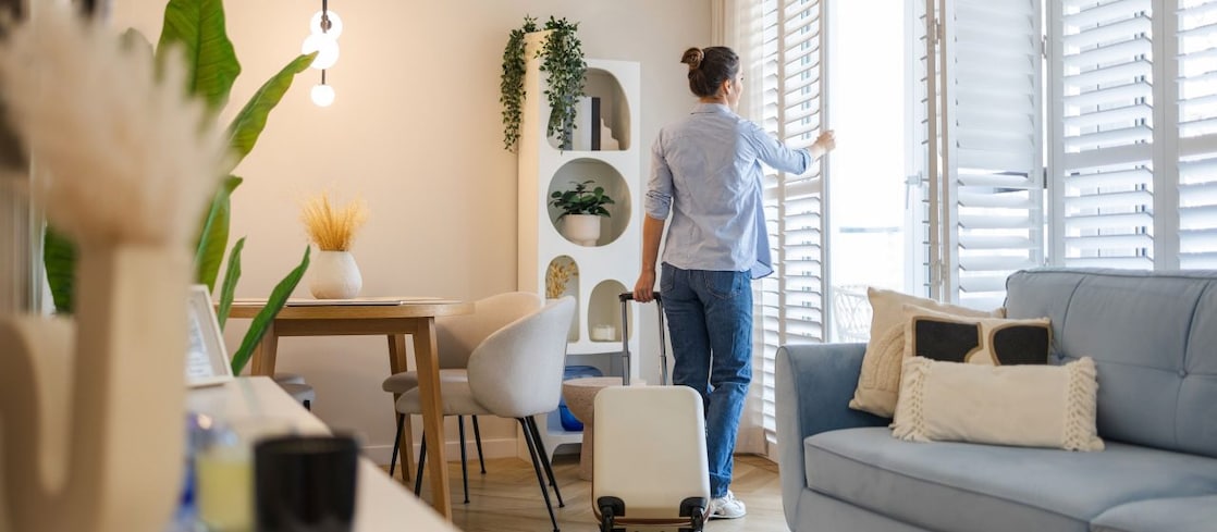 Junge Frau mit ihrem Koffer in einer Wohnung.