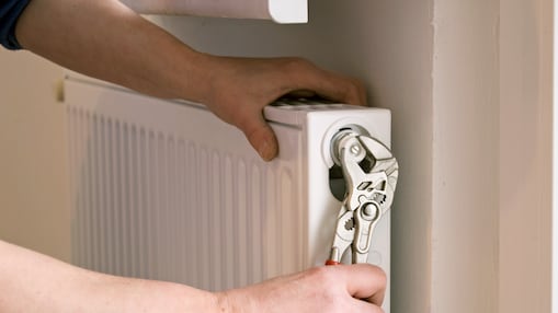 Hand mit Zange, die Heizung entlüftet