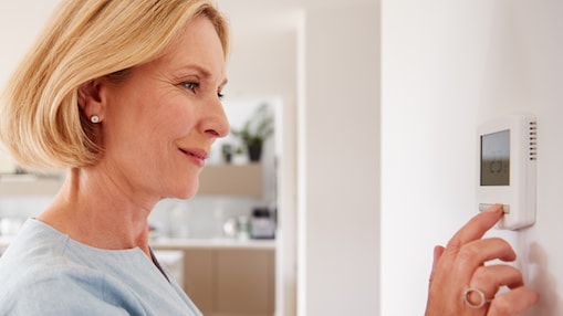 Blonde Frau am digitalen Heizungsthermostat