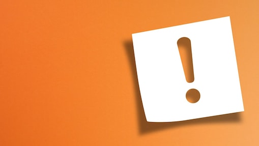 Notizpapier mit Ausrufezeichen auf orangenem Hintergrund