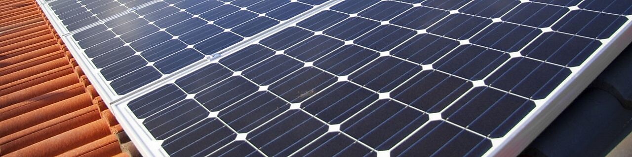 Dach mit Solar Panelen vor blauem Himmel