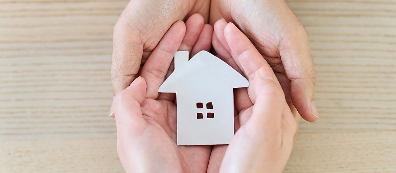 Ein Modellhaus wird in den insgesamt vier Händen gehalten