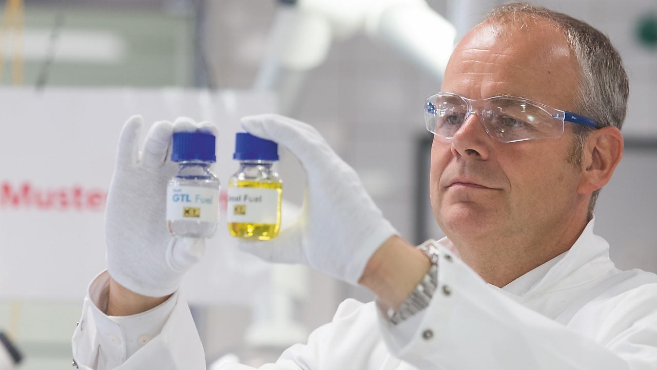 Ein Labormitarbeiter hält zwei Probefläschchen hoch und vergleicht deren Inhalt.