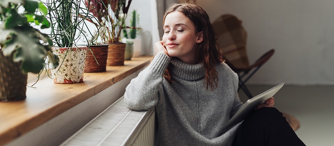 Eine Frau lehnt sich an ihre Heizung