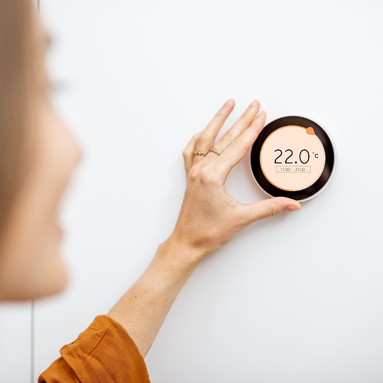 Frau dreht an digitaler Temperaturanzeige