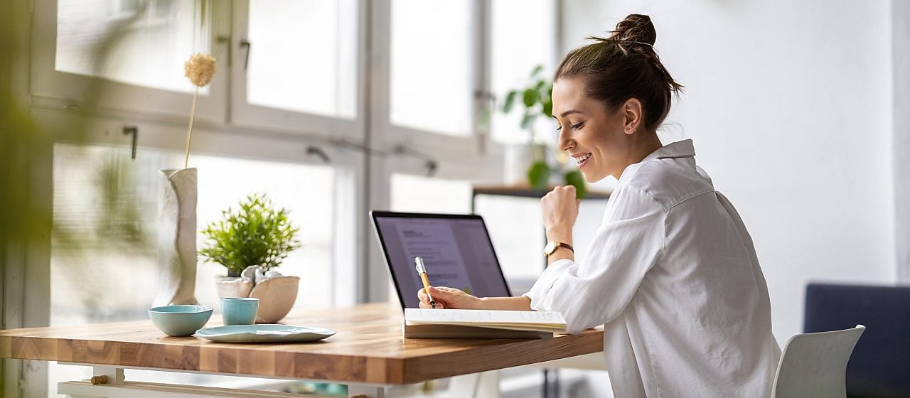 Frau am Schreibtisch mit Laptop und Stift