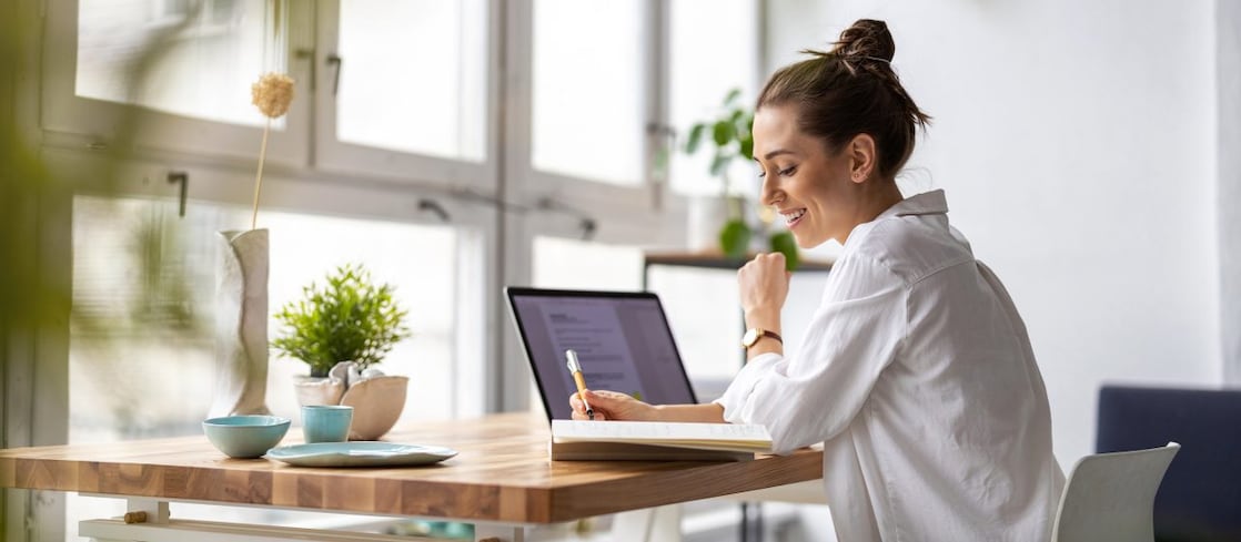 Frau am Schreibtisch mit Laptop und Stift