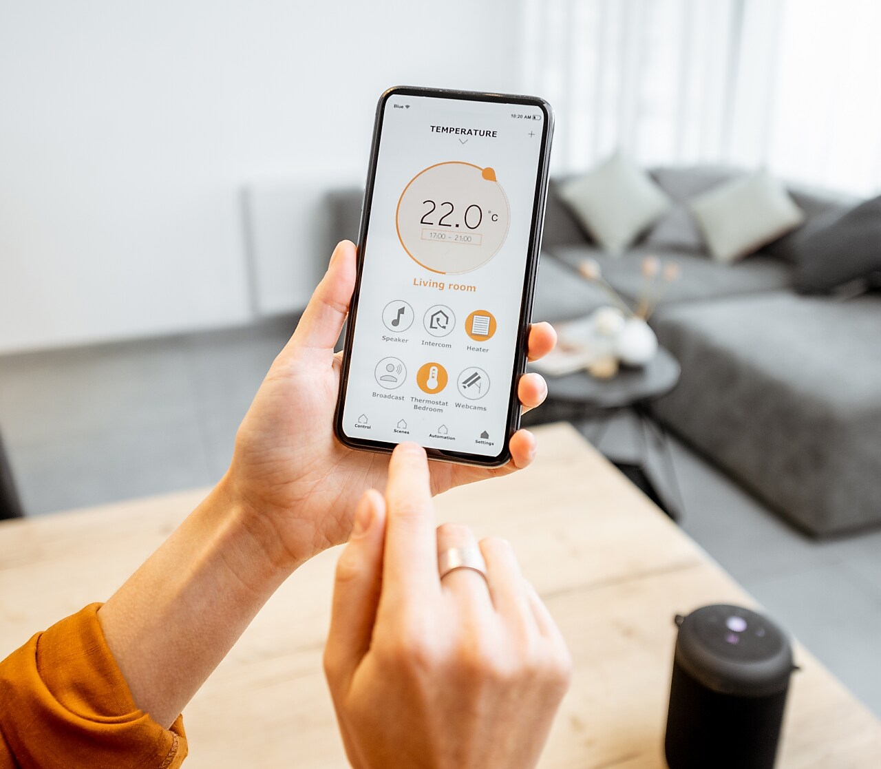 Hände tippend am Smartphone, Wohnzimmer im Hintergrund