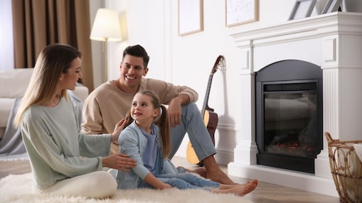 Familie sitzt zuhause vor dem Kamin