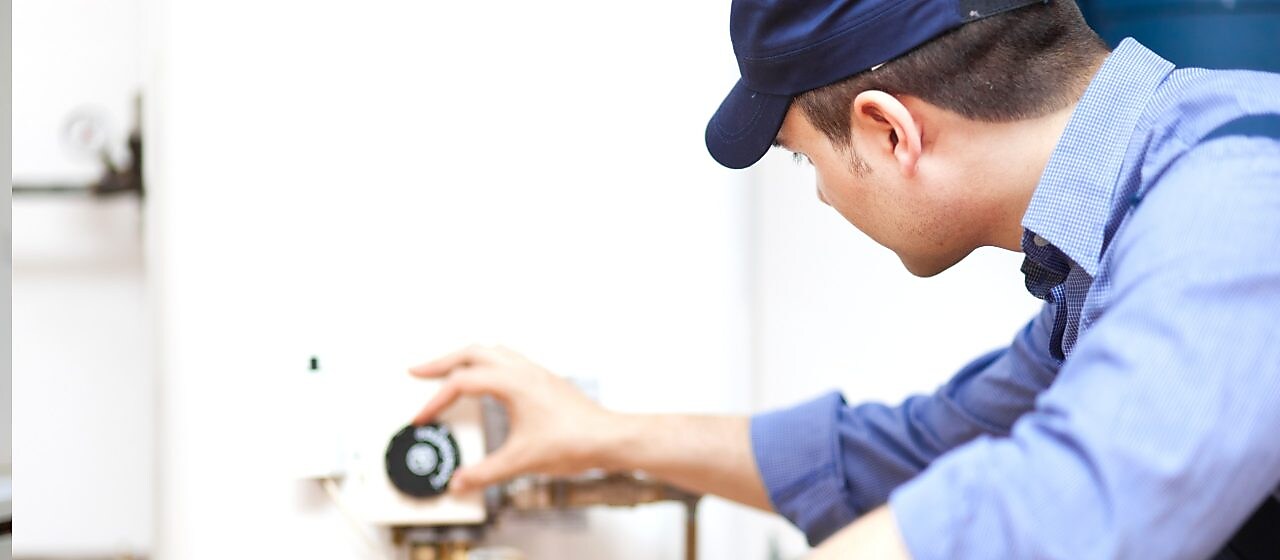 Ein Mann in einem Blaumann stellt die Heizung ein