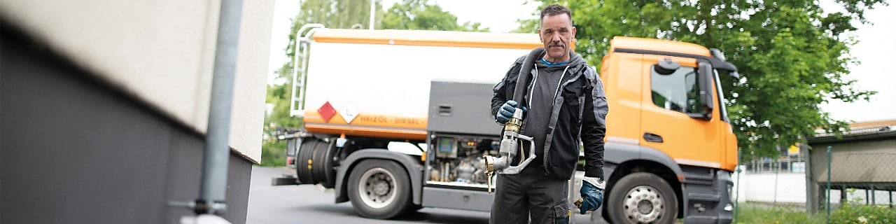Heizöl Tankwagenfahrer läuft mit dem Schlauch zum Heizungskeller