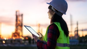 Eine Frau sitzt in einem hellen Raum vor einem Computer.