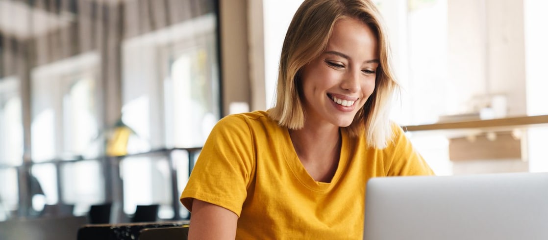Eine Frau sitzt lächelnd vor dem Laptop