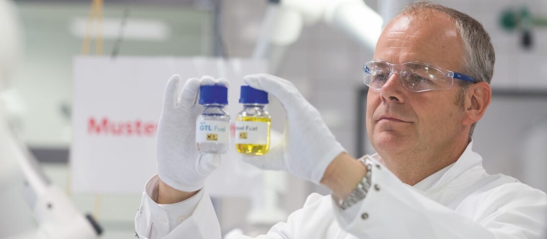 Ein Wissenschaftler hält zwei GTL Proben vor sich zum Abgleich
