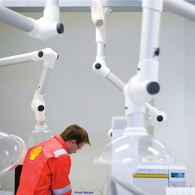 Ein Shell Mitarbeiterr steht in einem Labor umgeben von hochwertigen Geräten