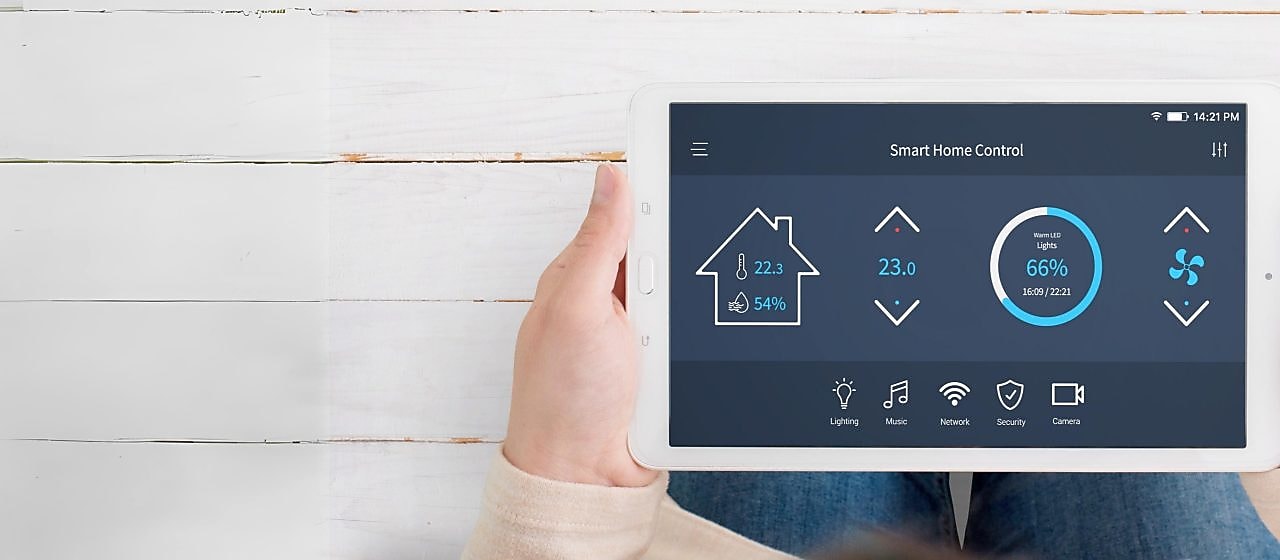Frau hält ein Tablet bei dem Smart Home Control geöffnet ist.