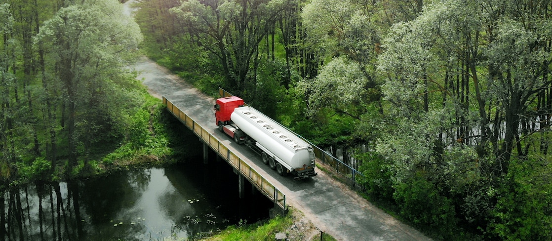 Ein Tanklaster, welcher über eine im Wald gelegene Brücke fährt