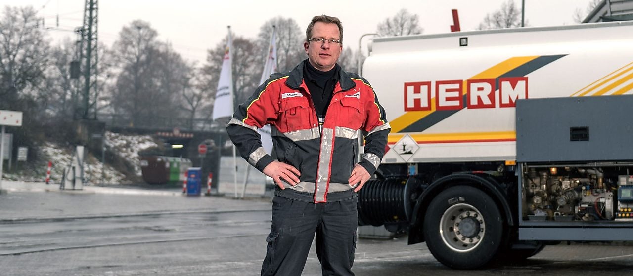 Herm GmbH Tankwagenfahrer steht neben Tankwagen
