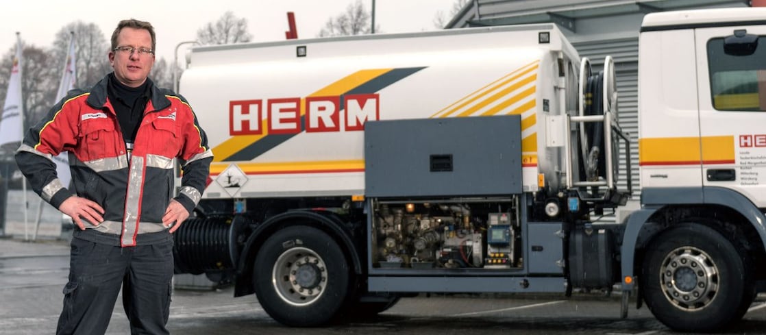 Herm GmbH Tankwagenfahrer steht neben Tankwagen