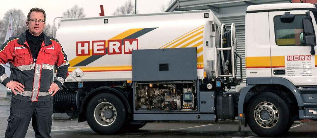 Herm GmbH Tankwagenfahrer steht neben Tankwagen