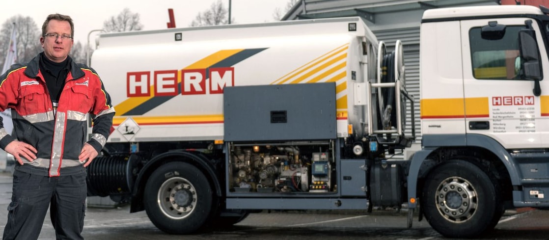 Herm GmbH Tankwagenfahrer steht neben Tankwagen