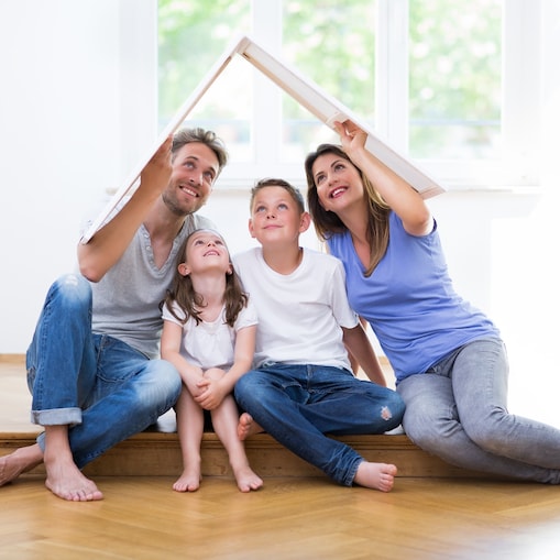 Eine Familie bedeckt sich mit einem Dach aus Pappe, um Schutz vor den Elementen zu finden.